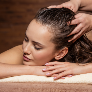 Woman with her eyes closed receiving a scalp massage.