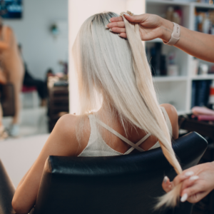 Hairstylist measuring blonde woman's hair growth. 