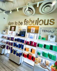 A salon wall with shelves displaying hair care products in colorful packaging under a sign reading "dare to be fabulous. A luxury hair care routine example. - Salon Jaylee | The Villages, FL