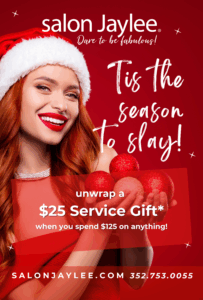 A smiling woman in a Santa hat holds red ornaments. The image advertises a $25 service gift at Salon Jaylee with a $125 purchase. Contact and website information are listed below. - Salon Jaylee | The Villages, FL